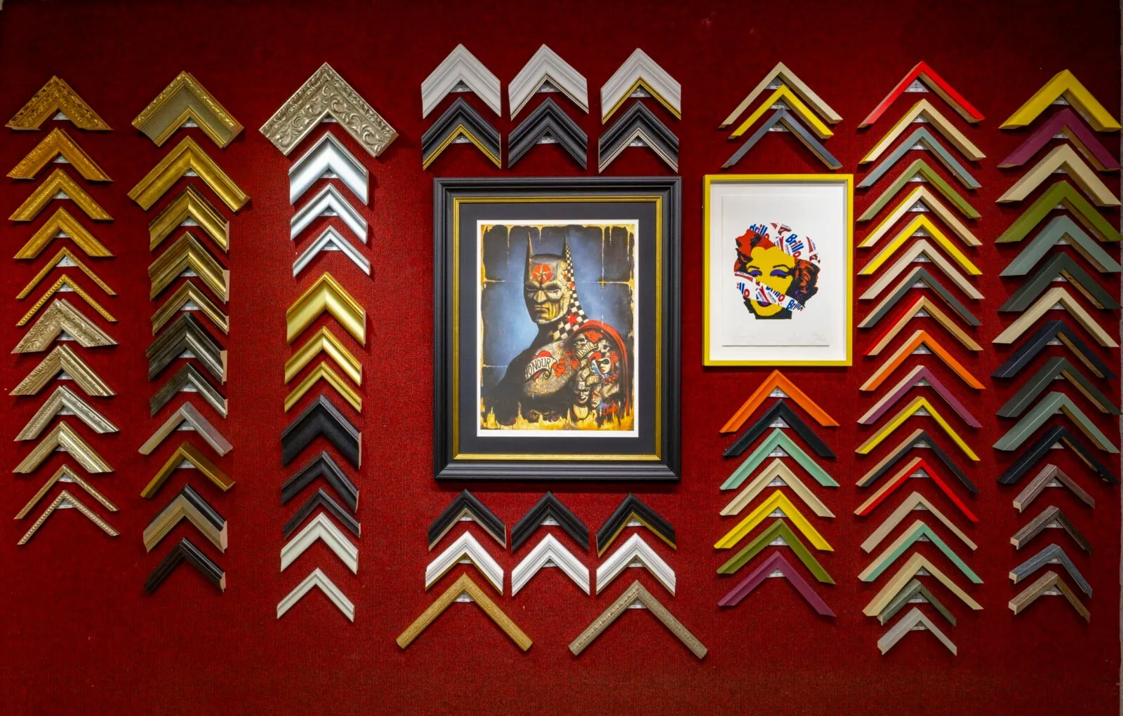 Picture frame moulding samples displayed on a red wall in the Concept Framing studio