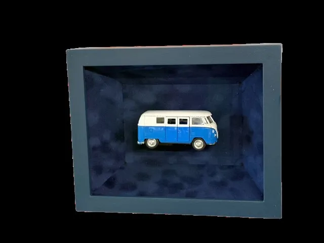 Blue and white toy VW camper van floated in a deep box frame lined with blue suede